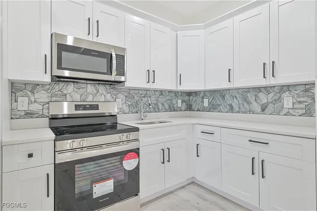 a kitchen with white cabinets and appliances