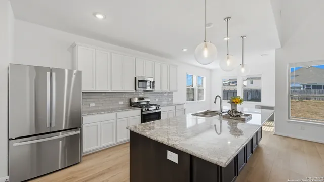 a kitchen with stainless steel appliances granite countertop a sink a stove a refrigerator cabinets and living room view