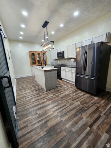 320 South State Street Preston, ID 83263 - Photo 3 of 20 Dual tone kitchen with freestanding refrigerator, range with two ovens, decorative light fixtures, tasteful backsplash, and dark wood finished floors