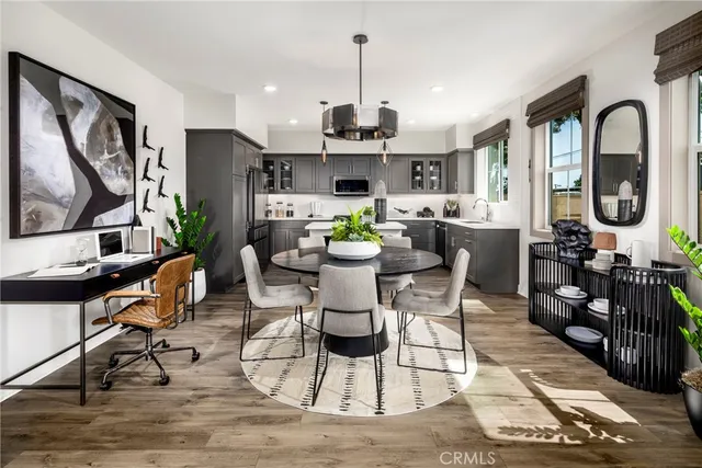a dining room with furniture a rug a potted plant and wooden floor