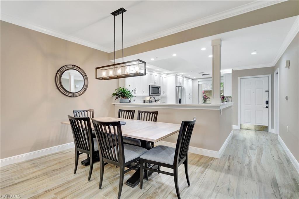 8630 Cedar Hammock Circle, Unit 1012 Naples, FL 34112 - Photo 11 of 37 a dining room with wooden floor a chandelier a wooden table and chairs