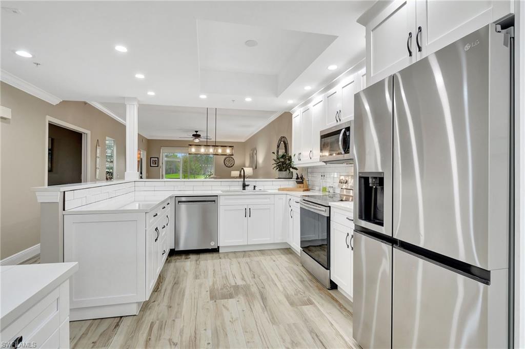8630 Cedar Hammock Circle, Unit 1012 Naples, FL 34112 - Photo 9 of 37 a kitchen with white cabinets and stainless steel appliances