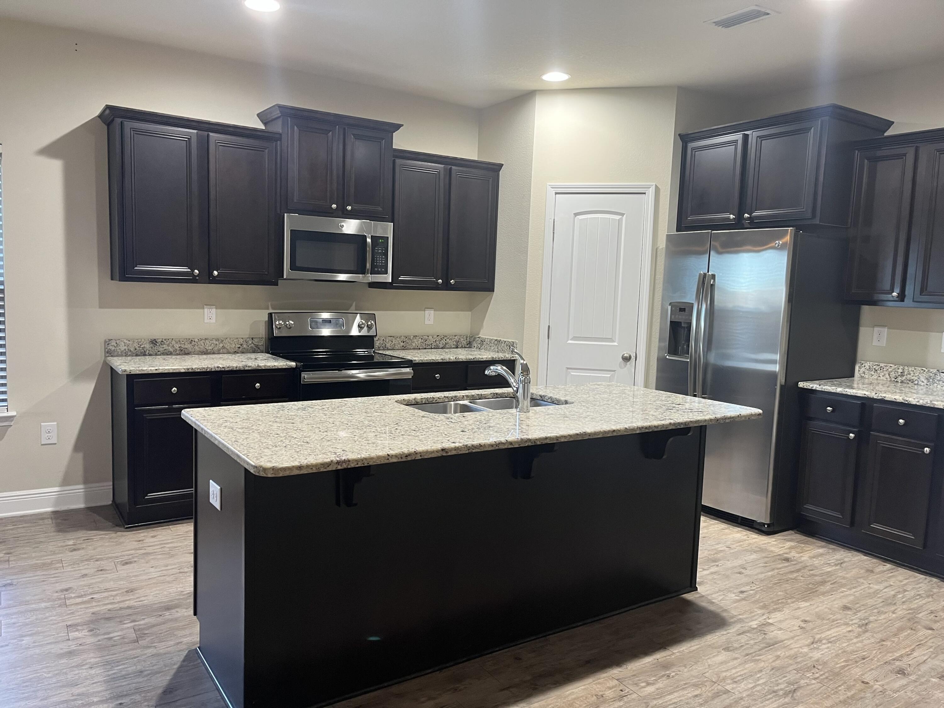 671 Teal Street Crestview, FL 32539 - Photo 7 of 22 a kitchen with kitchen island granite countertop wooden cabinets and a refrigerator