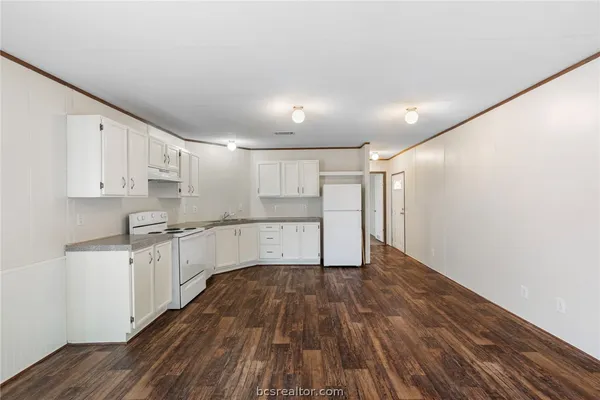 a large kitchen with wooden floor and stainless steel appliances