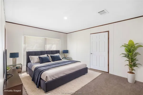 a bedroom with a large bed and a potted plant