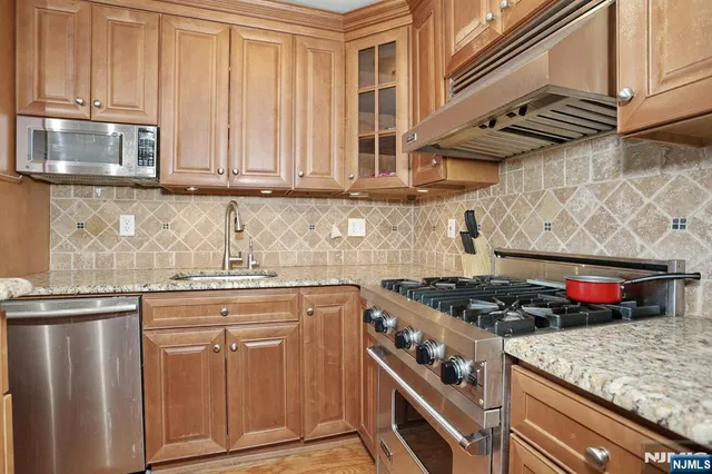 a kitchen with stainless steel appliances granite countertop a sink stove and microwave