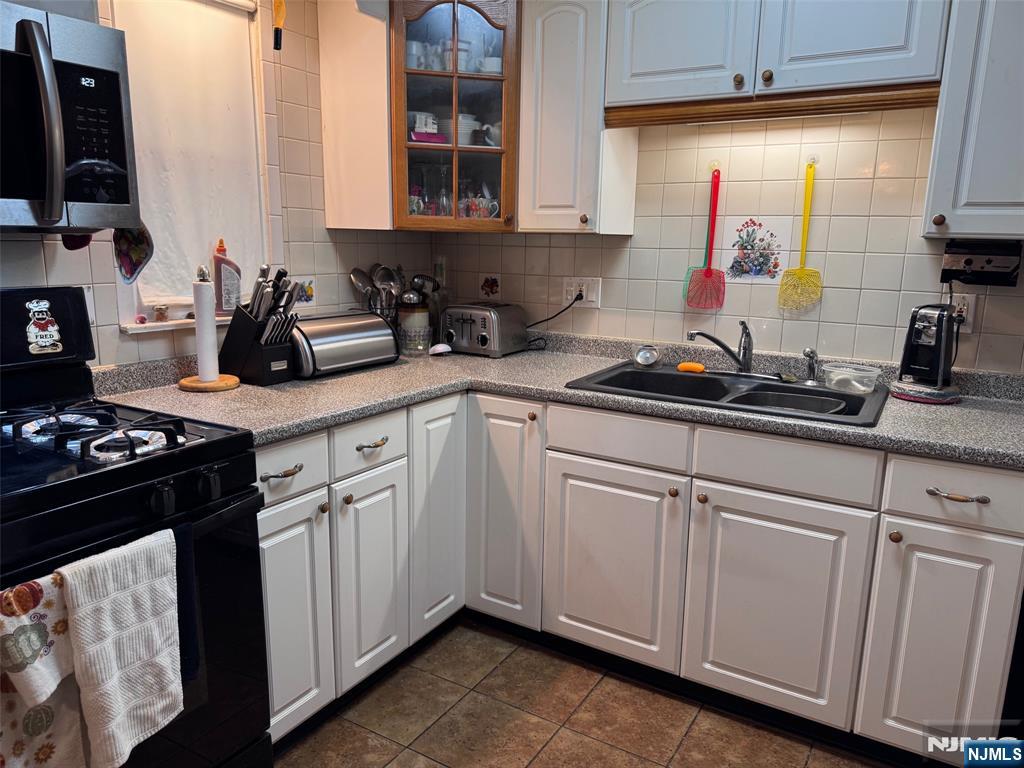 266 Hamilton Road Teaneck, NJ 07666 - Photo 6 of 27 a kitchen with white cabinets a sink dishwasher and a stove with wooden floor