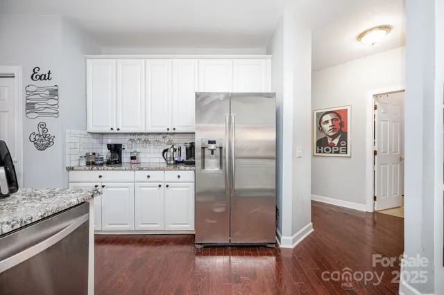 a kitchen with granite countertop stainless steel appliances a refrigerator sink and wooden floor