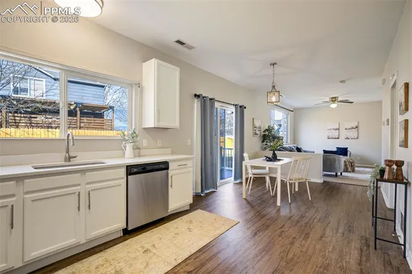 a kitchen with a dining table chairs wooden floor appliances and cabinets