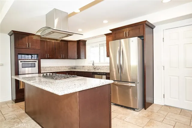 a kitchen with stainless steel appliances granite countertop a refrigerator a stove and a sink with wooden cabinets
