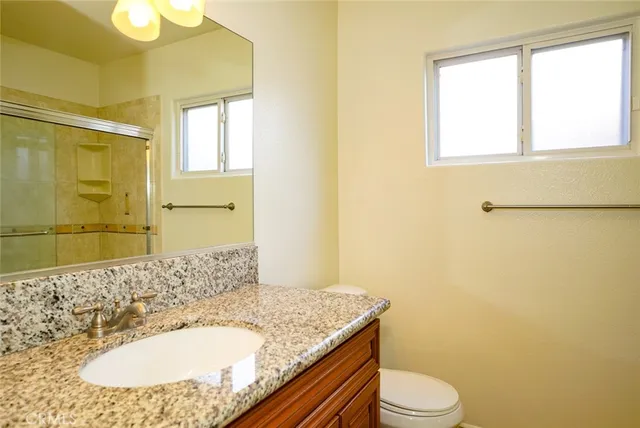 a bathroom with a granite countertop sink toilet and shower