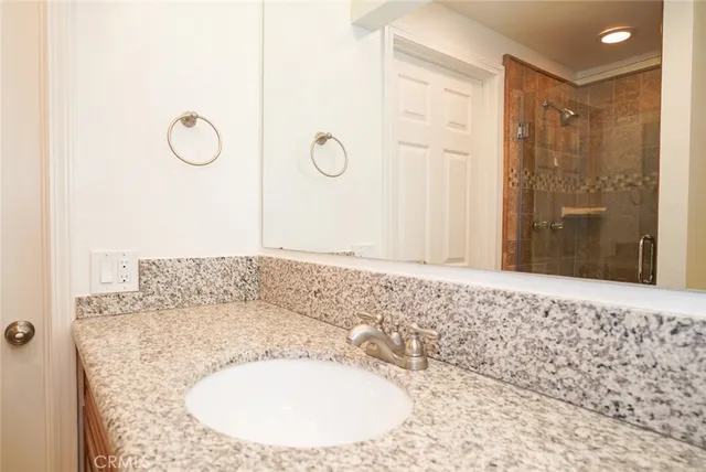 a bathroom with a granite countertop sink a mirror and shower