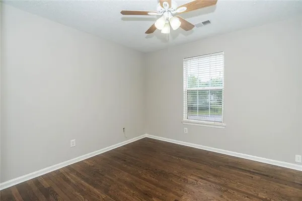an empty room with windows and ceiling fan
