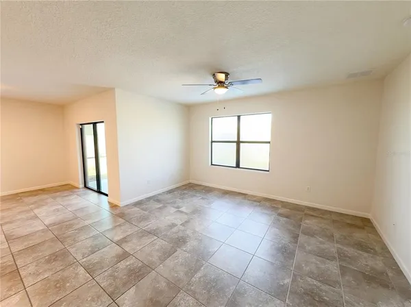 an empty room with windows and chandelier fan