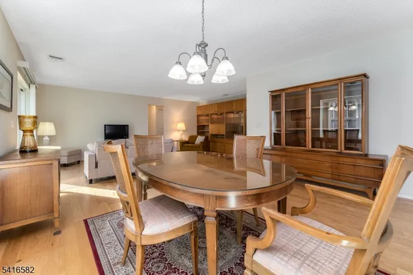 a dining room with wooden floor a chandelier a wooden table and chairs