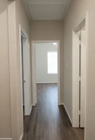 a view of hallway with window and wooden floor