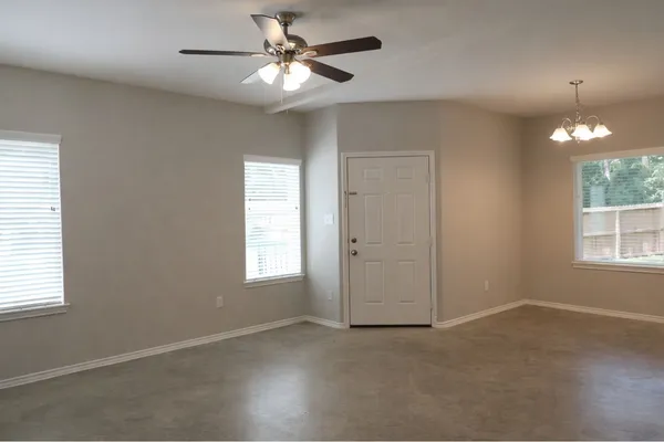 an empty room with windows and fan