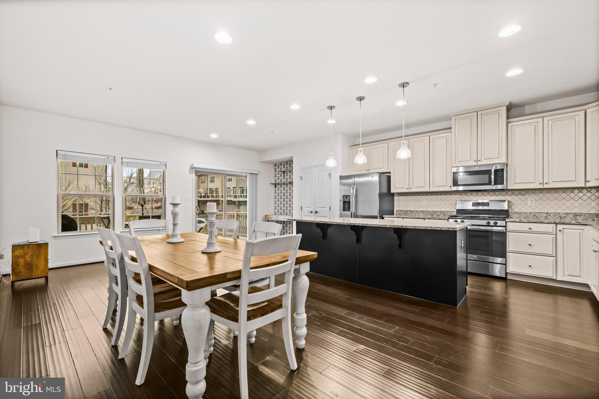 7839 Patterson Way Hanover, MD 21076 - Photo 12 of 56 a kitchen with stainless steel appliances kitchen island granite countertop a stove a sink a microwave a dining table and chairs with wooden floor