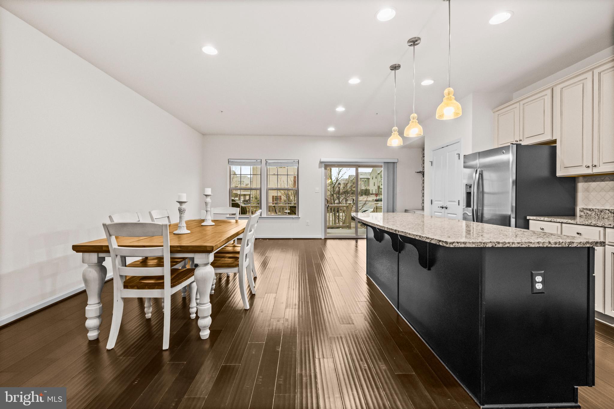 7839 Patterson Way Hanover, MD 21076 - Photo 13 of 56 a dining room with stainless steel appliances kitchen island granite countertop a stove top oven a dining table and chairs with wooden floor