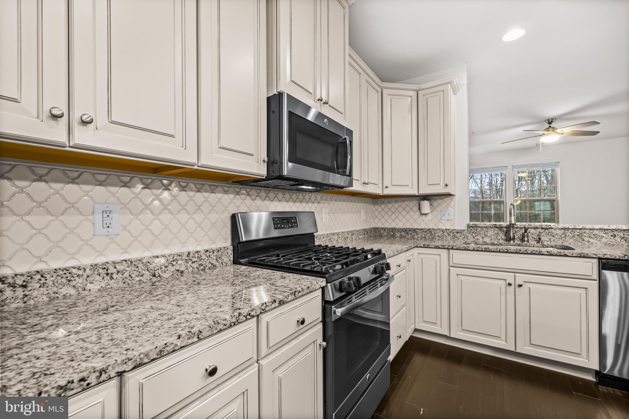 7839 Patterson Way Hanover, MD 21076 - Photo 21 of 56 a kitchen with granite countertop white cabinets and a stove top oven