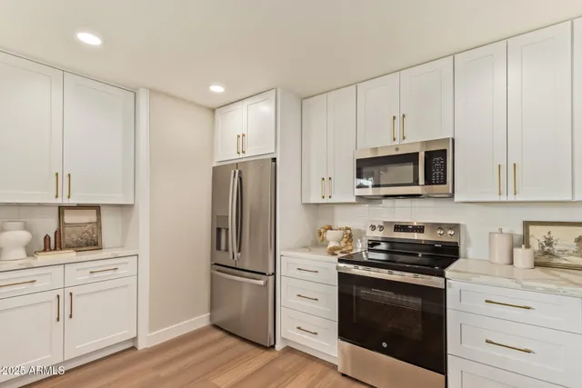 a kitchen with white cabinets and stainless steel appliances