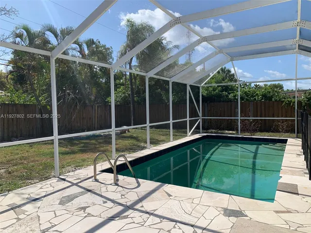 a view of a backyard with floor to ceiling window and wooden fence