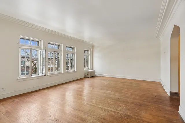 a view of an empty room with a window and wooden floor