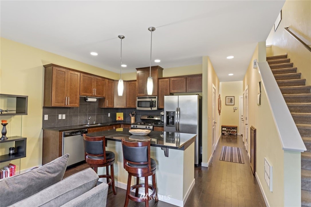 111 164th Place Southeast Bothell, WA 98012 - Photo 4 of 27 a kitchen with stainless steel appliances kitchen island granite countertop a refrigerator a stove a sink a dining table and chairs with wooden floor