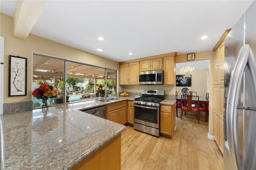 19320 Totem Court Riverside, CA 92508 - Photo 15 of 53 Bright kitchen with granite countertops, generous cabinetry, and stainless steel appliances, plus a large window framing the backyard/pool view.