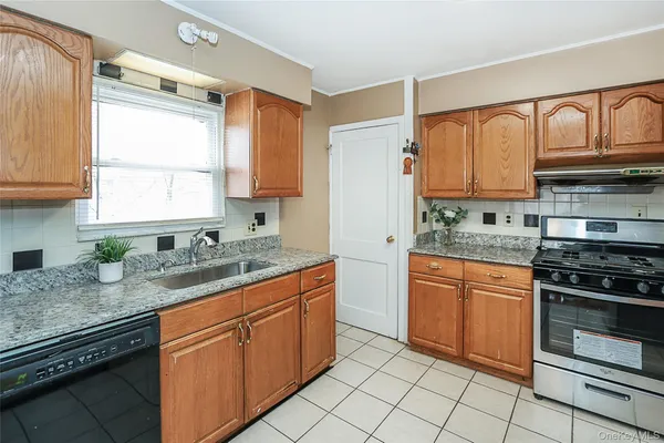 a kitchen with granite countertop stainless steel appliances a sink window and cabinets