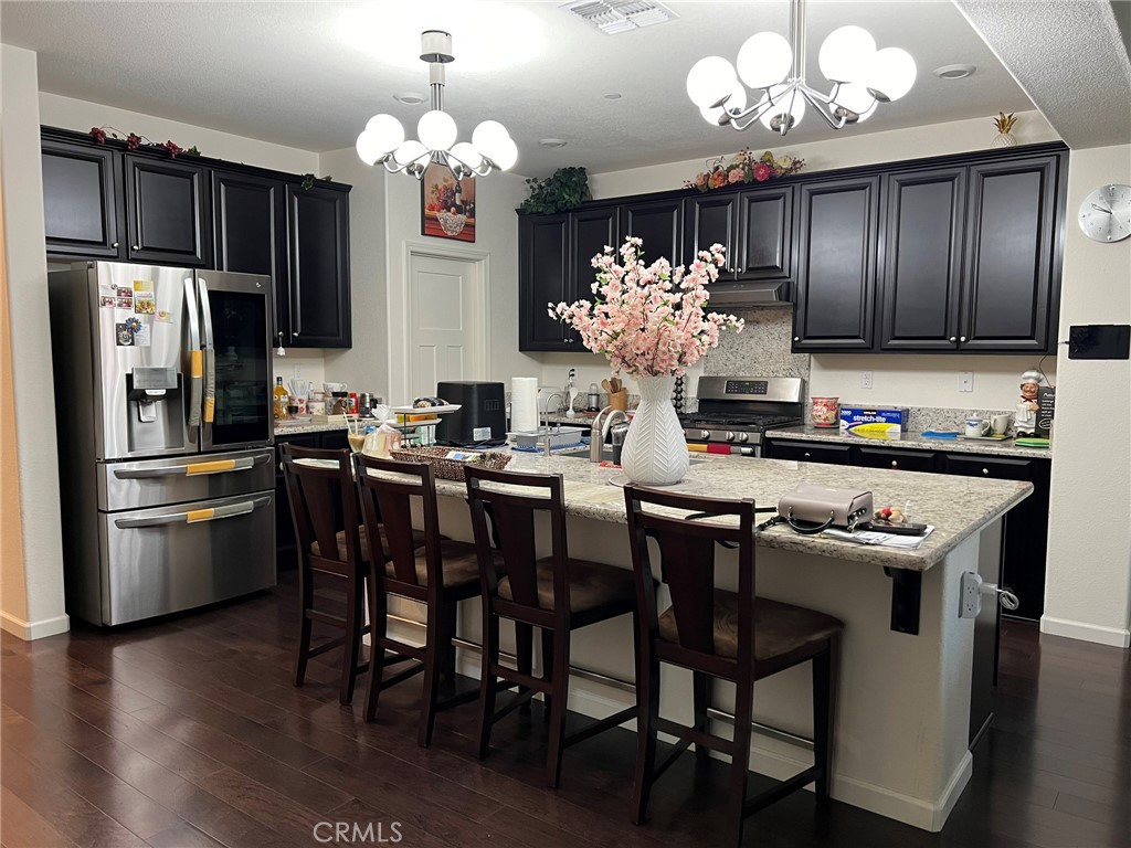 a kitchen with kitchen island granite countertop stainless steel appliances a table and chairs in it