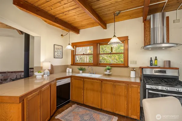 a dining hall with stainless steel appliances granite countertop a stove a sink dishwasher and chairs
