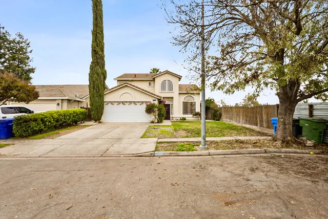 a view of a house with a yard and large tree