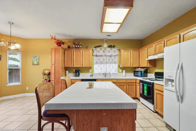 a kitchen with stainless steel appliances granite countertop a table chairs sink refrigerator and microwave