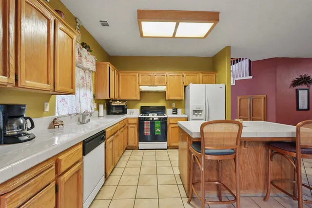 a kitchen with stainless steel appliances granite countertop wooden cabinets a stove top oven a sink and dishwasher