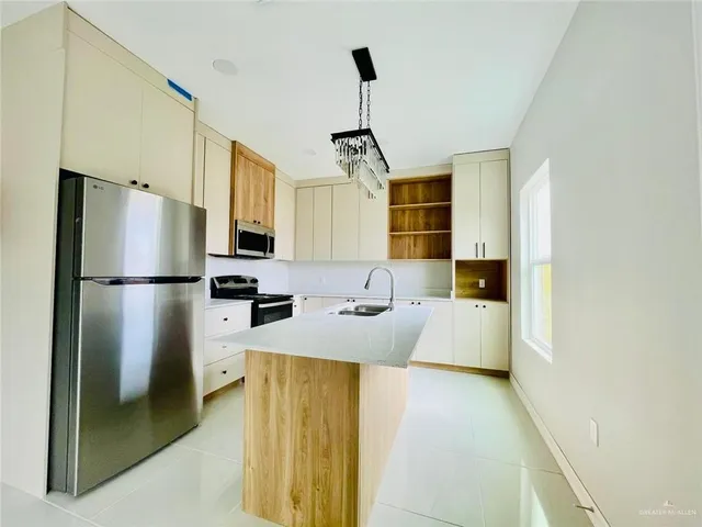 a kitchen with stainless steel appliances granite countertop a refrigerator a stove a sink dishwasher and a refrigerator with wooden floor