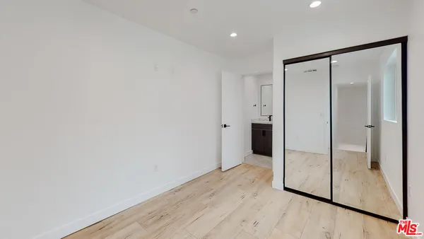 a view of an empty room with wooden floor and a bathroom