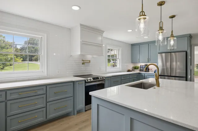 a large kitchen with kitchen island a large counter space a sink appliances and cabinets