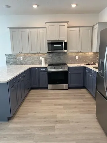 a large kitchen with granite countertop a stove top oven microwave and cabinets