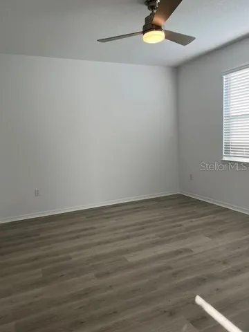 a view of an empty room with wooden floor and a window