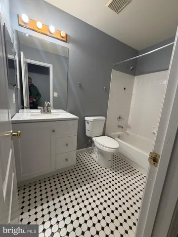 a view of a hallway with wooden floor and a bathroom