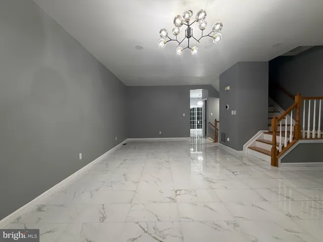 a view of an empty room with a chandelier fan