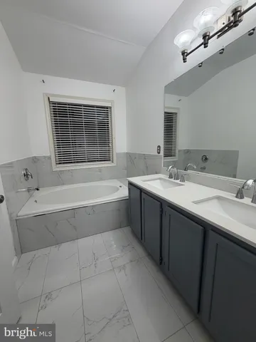 a spacious bathroom with a tub sink and mirror