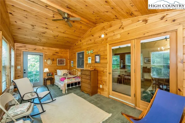 a living room with furniture a flat screen tv and floor to ceiling window