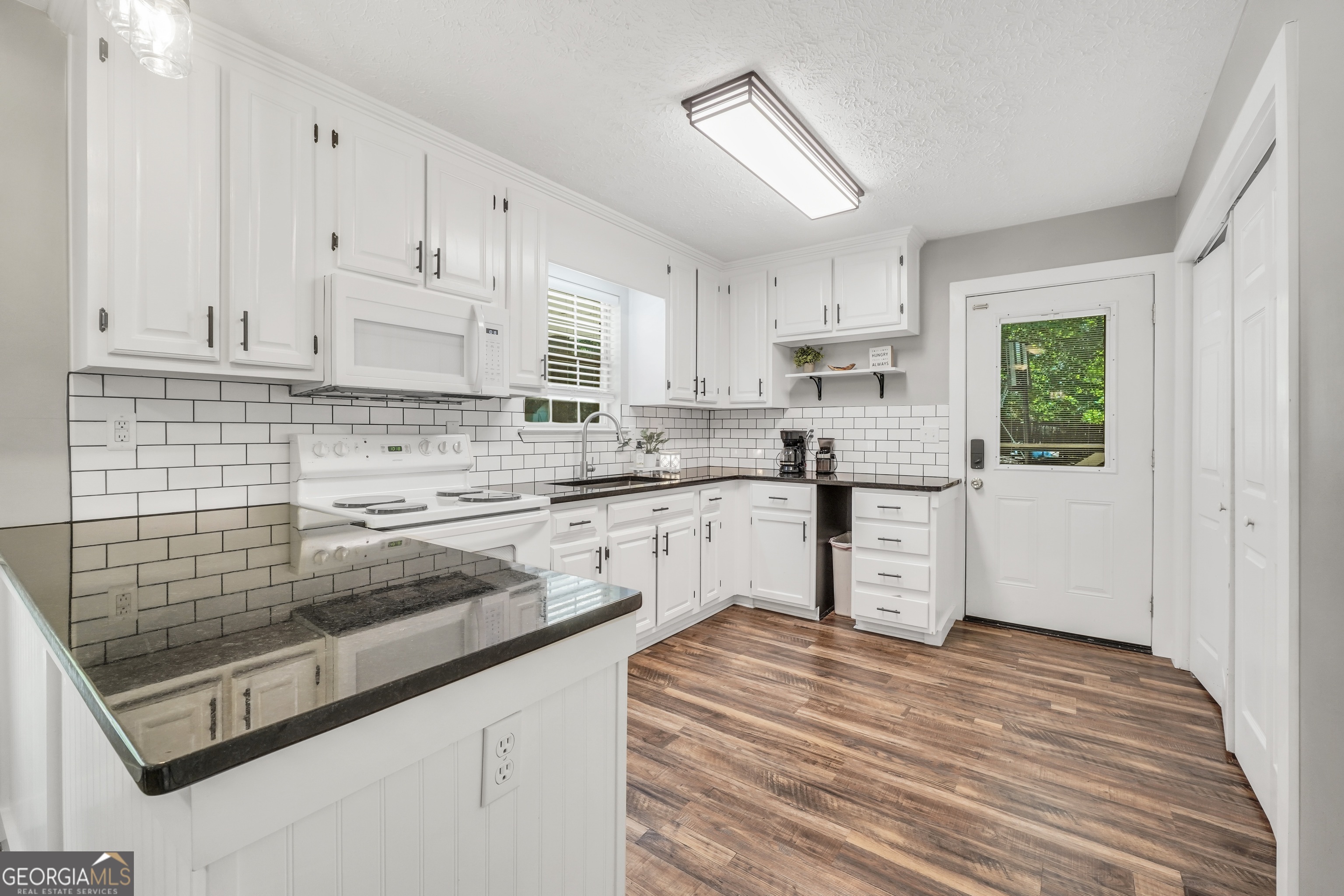 533 Chuli Road Griffin, GA 30223 - Photo 30 of 53 a kitchen with granite countertop white cabinets and white appliances