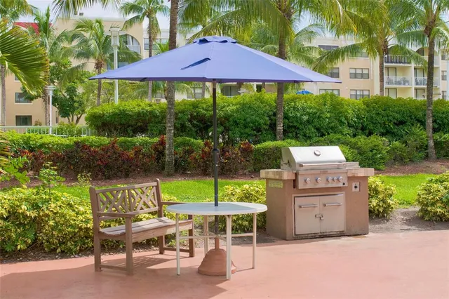 a view of a chairs and table under an umbrella in front of house