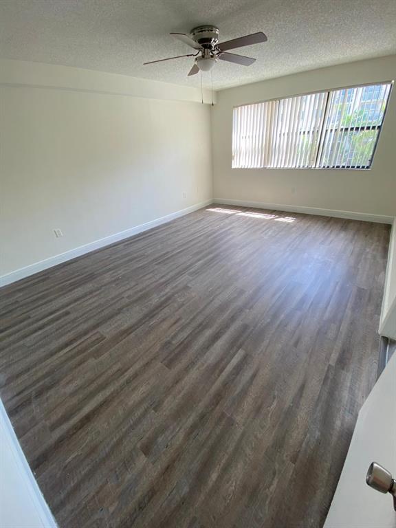 18335 Northwest 68th Avenue, Unit 790220 Hialeah, FL 33015 - Photo 6 of 14 an empty room with wooden floor fan and windows