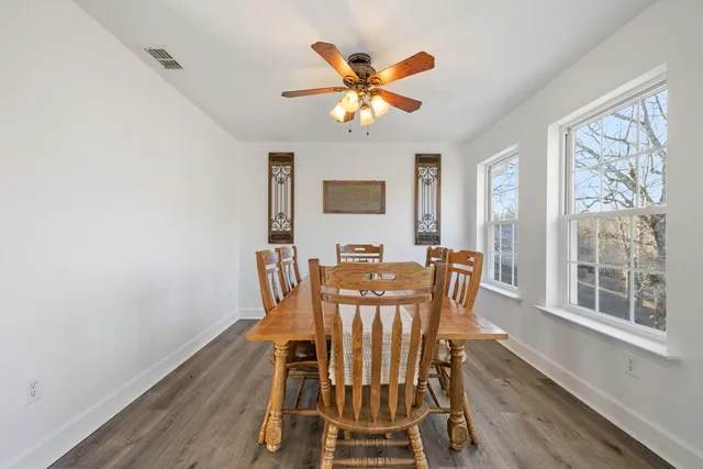 a dining room with furniture a large window and wooden floor