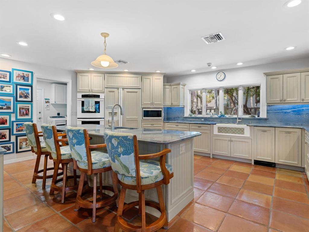 3300 Casey Key Road Nokomis, FL 34275 - Photo 12 of 65 a kitchen with stainless steel appliances kitchen island granite countertop a table chairs sink and cabinets