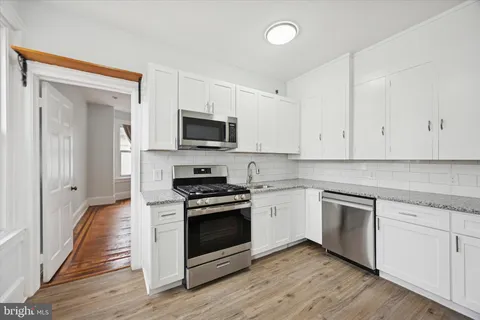 a kitchen with cabinets stainless steel appliances and wooden floor